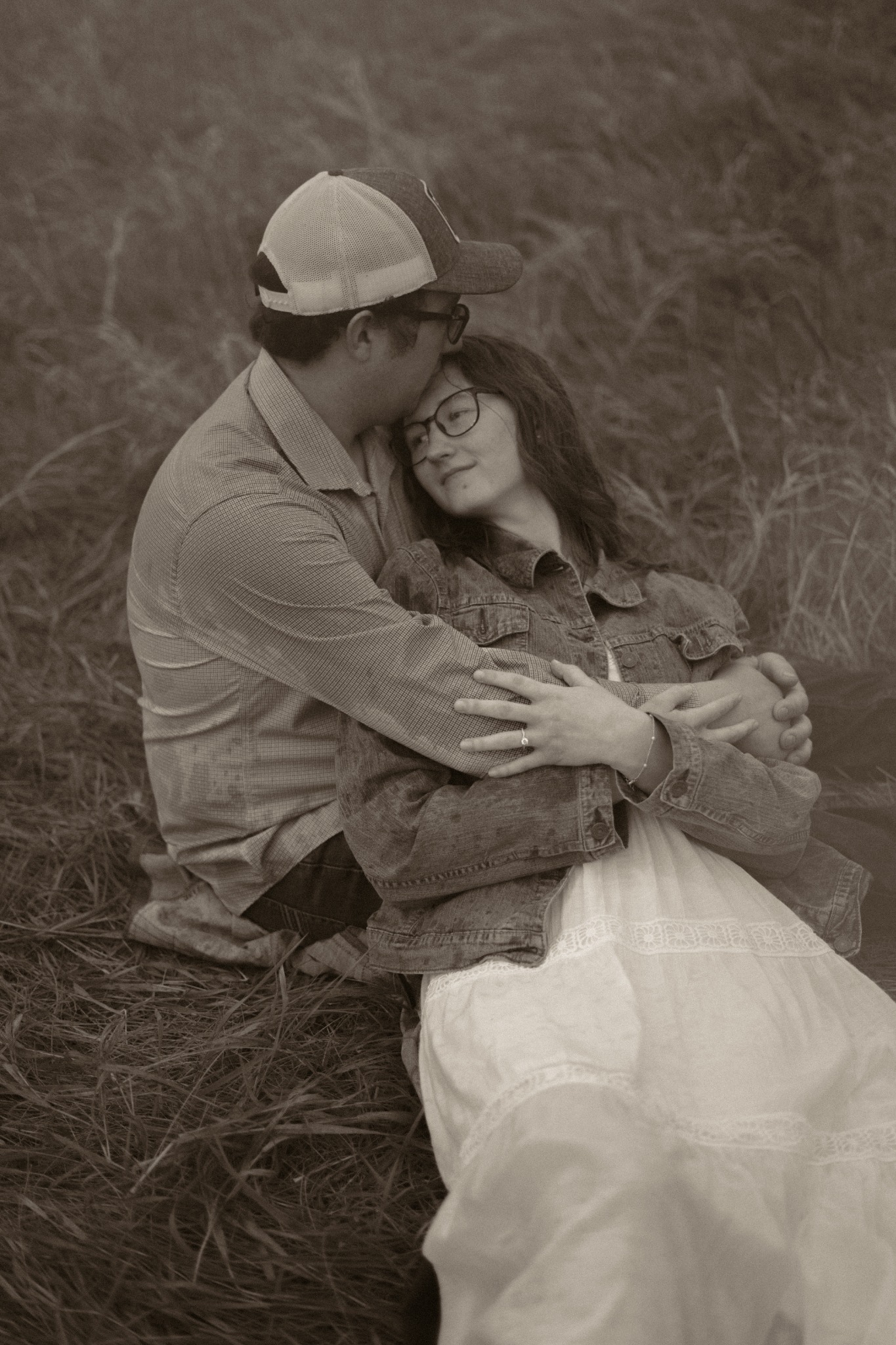 An engaged couple resting together in a field