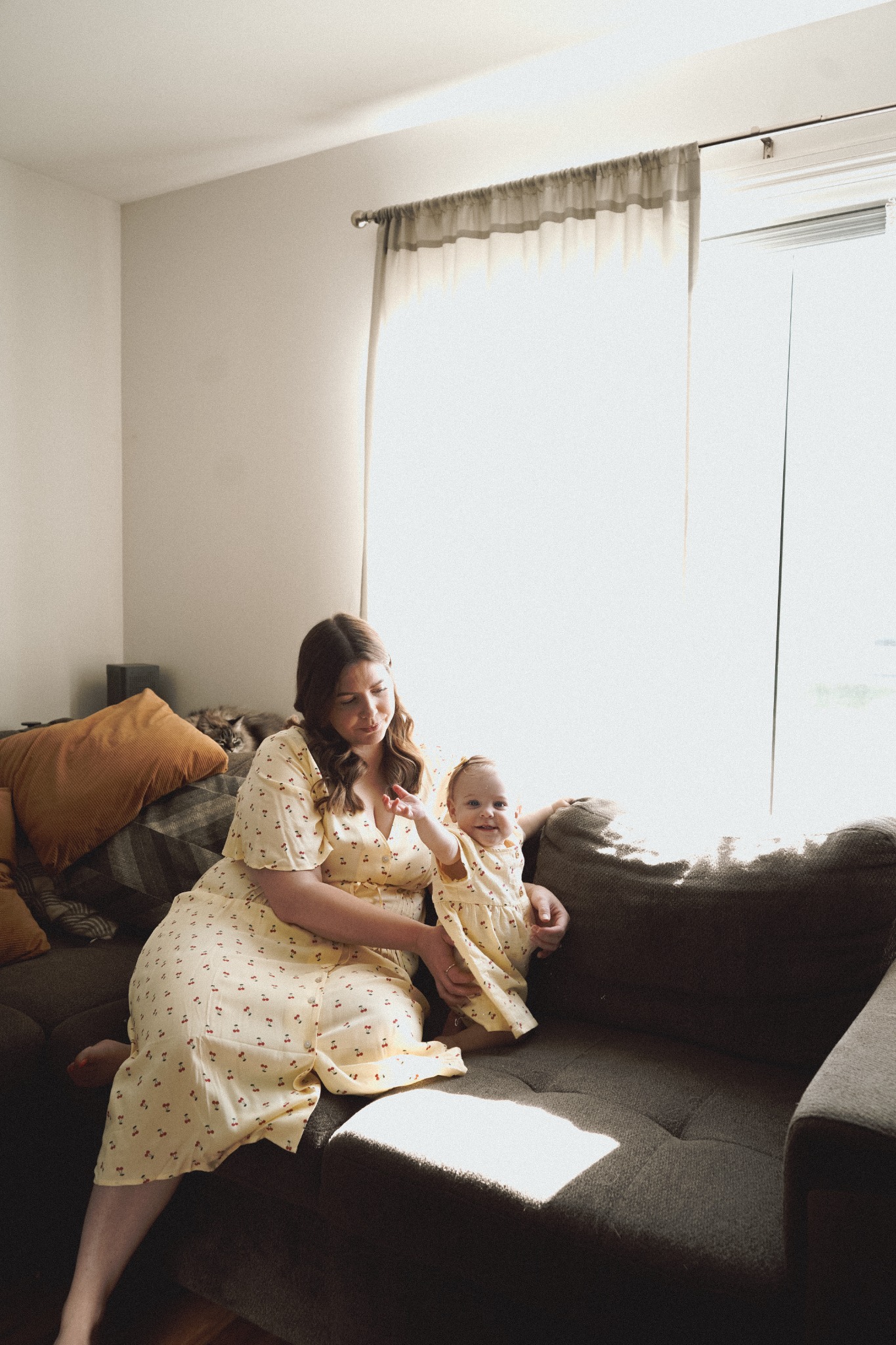 A mother holding her baby beside a window at home